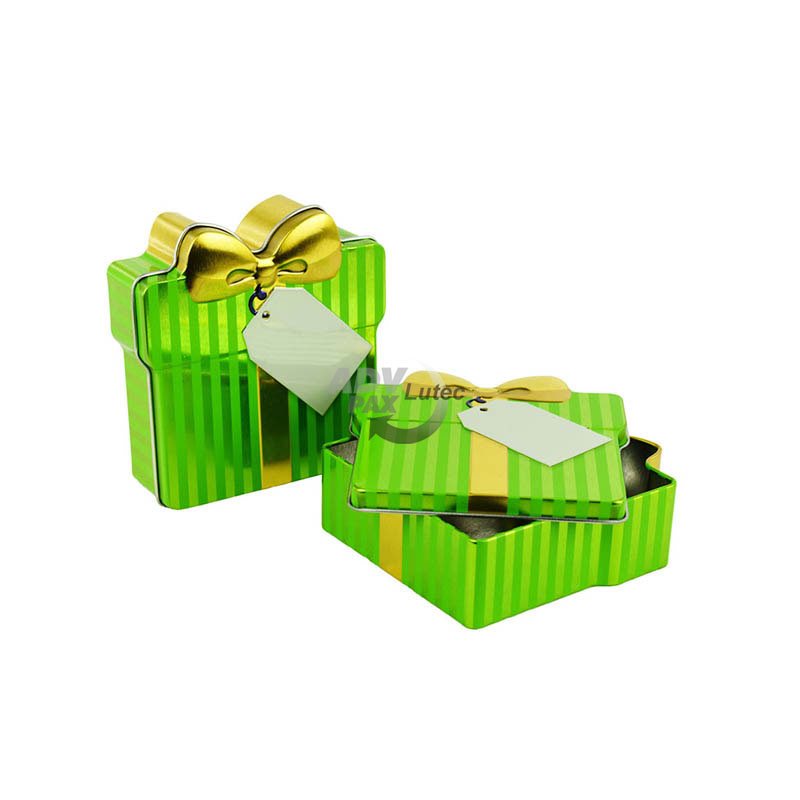 Schmuckdose Geschenkdose grün gestreift mit goldener stilisierter Schleife, Weißblechdose halb geöffnet im Vordergrund liegend, zweite geschlossen stehend
