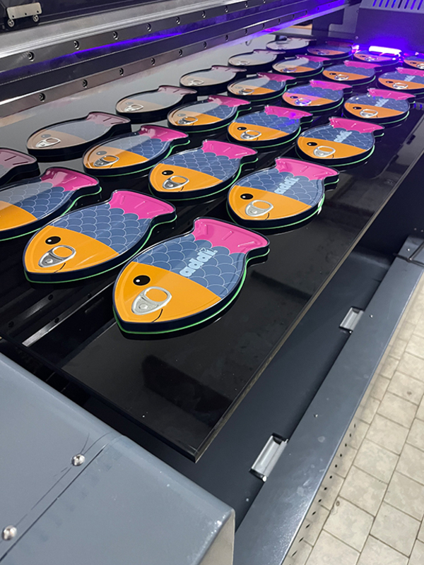 Digitaldruckmaschine bei ADV PAX Lutec, erste Reihe der Fish Tin Sonderform-Fischdosen bereits mit Kundenlogo personalisiert – hochwertige Metallverpackungen in Produktion.