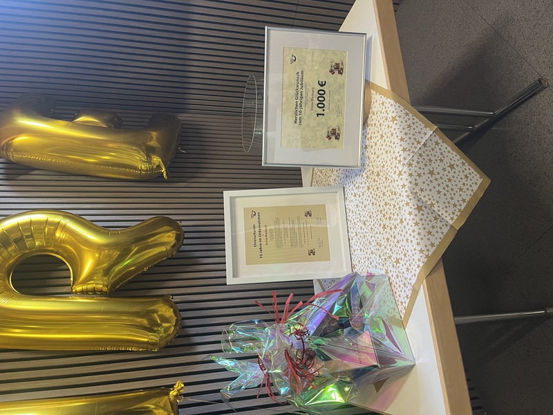 Geschenktisch mit Ehrenurkunde, Gutschein und individuell bedruckter Dose zum 10-jährigen Jubiläum bei ADV PAX Lutec GmbH