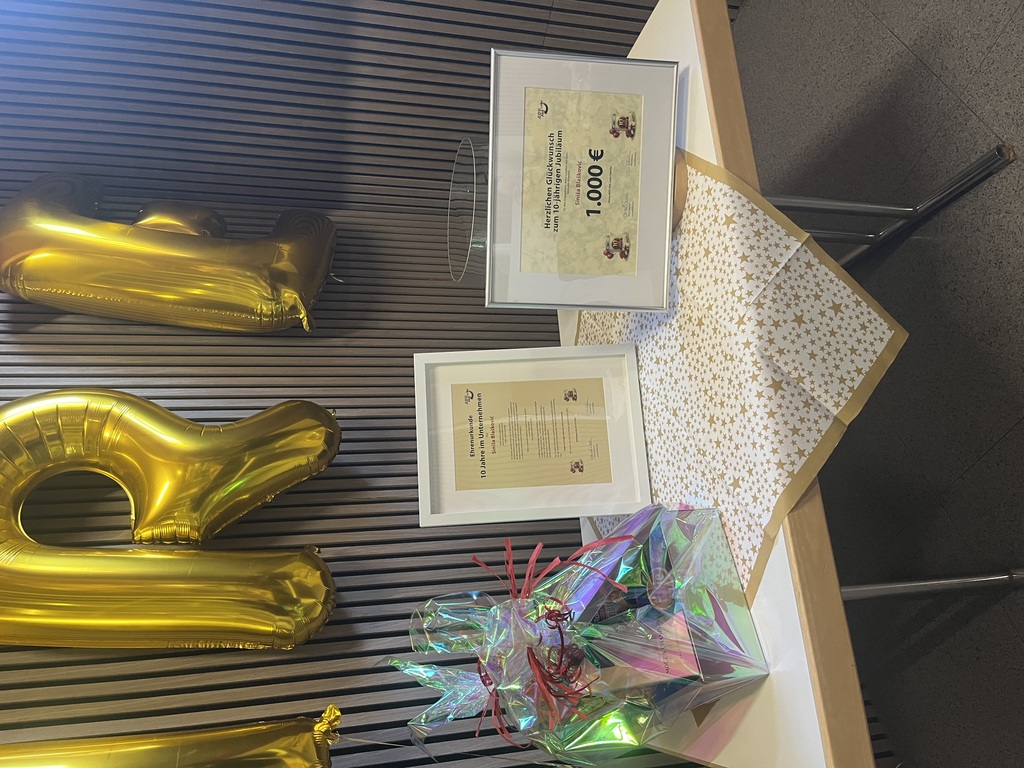 Geschenktisch mit Ehrenurkunde, Gutschein und individuell bedruckter Dose zum 10-jährigen Jubiläum bei ADV PAX Lutec GmbH